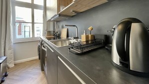 A modern kitchen with a stainless steel sink, a kettle, and a dish rack. - Apartment Villa Anna - Apartment with parking space (Emden)