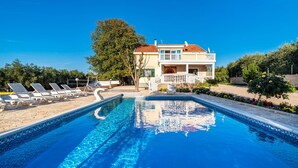 A swimming pool with lounge chairs, a house with a balcony, and a garden. - Pet friendly home in Polaca (Polaca)