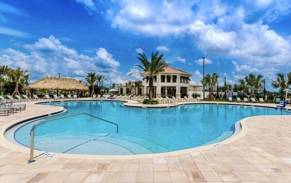 A swimming pool with lounge chairs and a building with a red roof.