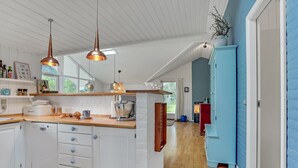 Una cocina moderna con armarios blancos, encimera de madera e iluminación colgante.