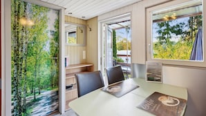 A room with a dining table, chairs, a bookshelf, and a view of trees through a window. - Amazing home in Zeulenroda-Triebes with sauna (Zeulenroda-Triebes)