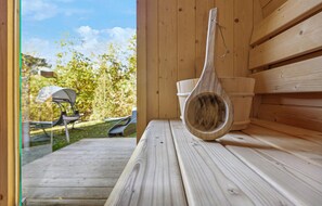 Un banco de madera con una cuchara de madera rústica encima, frente a una pared de madera, con vista a un jardín y un área de estar al aire libre visible a través de una puerta abierta.