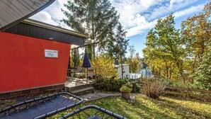 A red building with a sign reading "Ferienhaus 219" and a covered outdoor seating area with a table and chairs. - Amazing home in Zeulenroda-Triebes with sauna (Zeulenroda-Triebes)