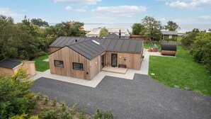 Et moderne træhus med skrå tag, en overdækket terrasse og et spabad i baghaven.