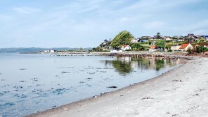 En kystby med en sandstrand, roligt vand og huse med røde tage.