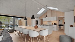 Et moderne køkken med hvide skabe, en central ø og hængende lamper.