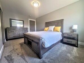 Ein Schlafzimmer mit einem großen Bett, einem Schminktisch, einem Nachttisch und einem Spiegel.