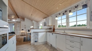 A modern kitchen with white cabinets, a wooden ceiling, and a large window providing natural light. - Gorgeous home in Skjern with WiFi (Skjern)