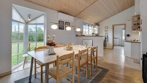 A spacious kitchen with wooden flooring, a dining area with a large table and chairs, and a view of the outdoors through large windows. - Gorgeous home in Skjern with WiFi (Skjern)