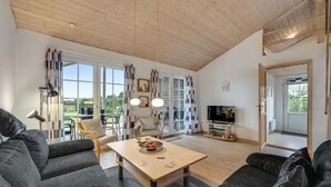 A spacious living room with a large window, a television, and a dining area with a table and chairs. - Gorgeous home in Skjern with WiFi (Skjern)