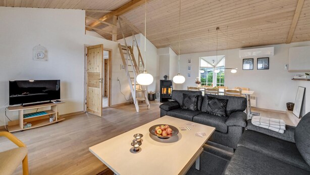 A spacious living room with a wooden ceiling, a sofa, a TV, and a dining area with a table and chairs. - Gorgeous home in Skjern with WiFi (Skjern)