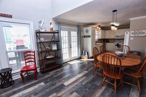Una cocina compacta con zona de comedor, que incluye una mesa y sillas de madera, un horno empotrado y un letrero que dice "BEACH HOUSE".