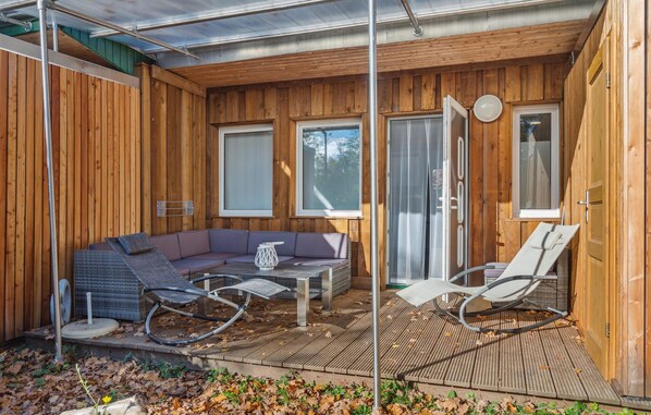 A wooden cabin with a patio area featuring a sofa, chairs, and a table.