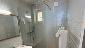 Ein modernes Badezimmer mit Duschkabine aus Glas, einem Holzwaschtisch mit Waschbecken und einem Spiegel.