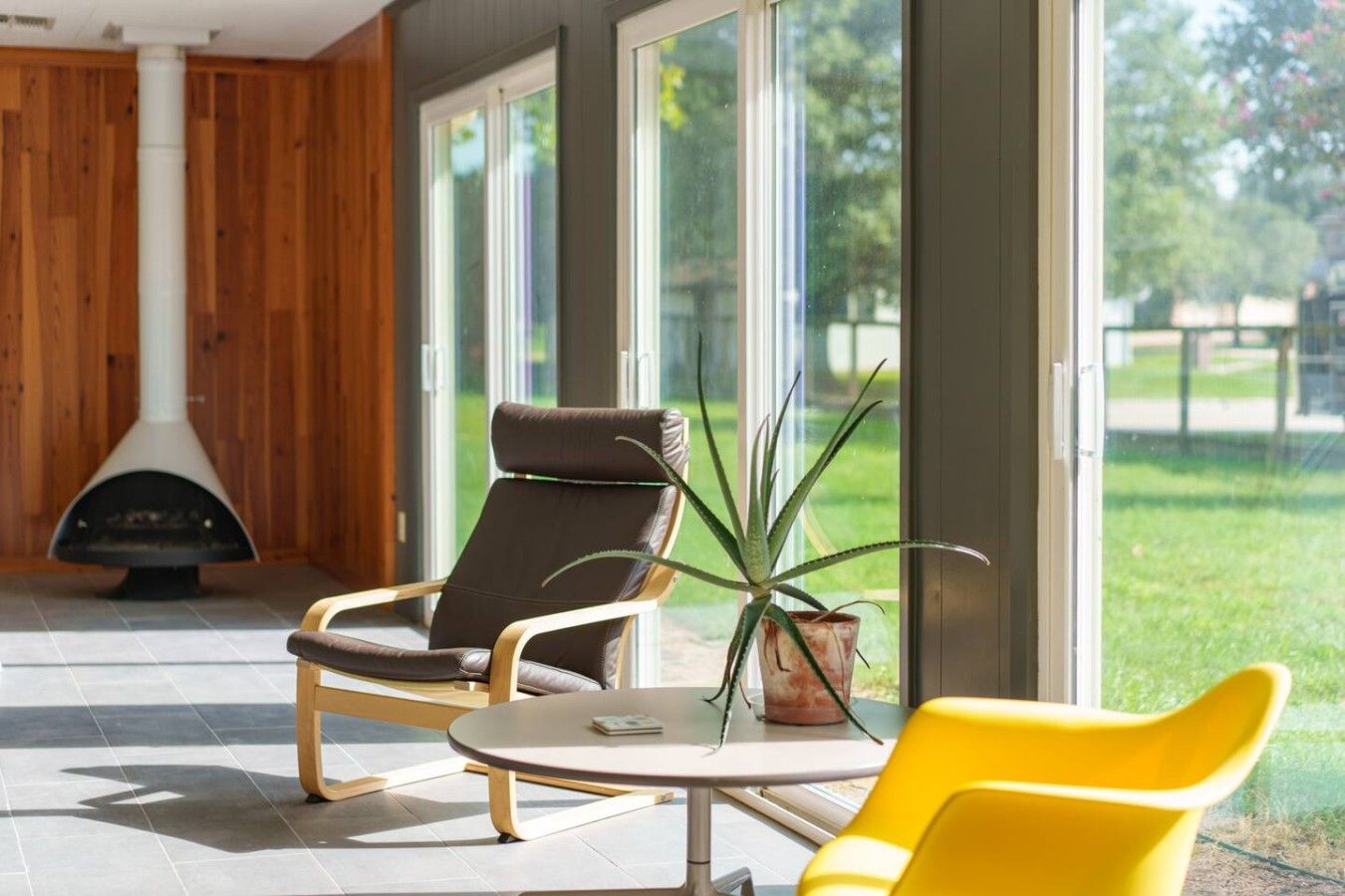 A modern interior with a fireplace, two chairs, a table, and a potted plant.