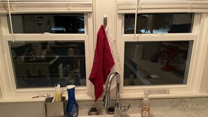 Una cucina con un lavello doppio, un asciugamano rosso appeso al rubinetto e una bottiglia di sapone per le mani.