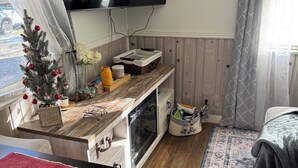 Una stanza accogliente con un mobile TV in legno, un piccolo abete decorato e un'ampia finestra con tende.