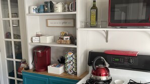 Una cucina con mobili color acquamarina, un bollitore rosso, un fornello e un forno a microonde.