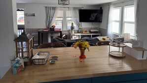 Un accogliente soggiorno con tavolino in legno, TV a parete e zona pranzo con tavolo e sedie.