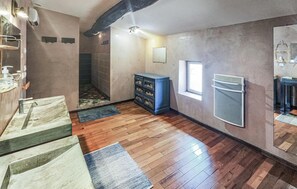 Ein Badezimmer mit Holzboden, Waschbecken, Dusche und einem blauen Stauraum.