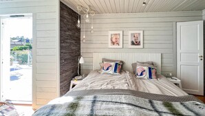Un dormitorio con una cama, dos mesitas de noche, una lámpara y una puerta.