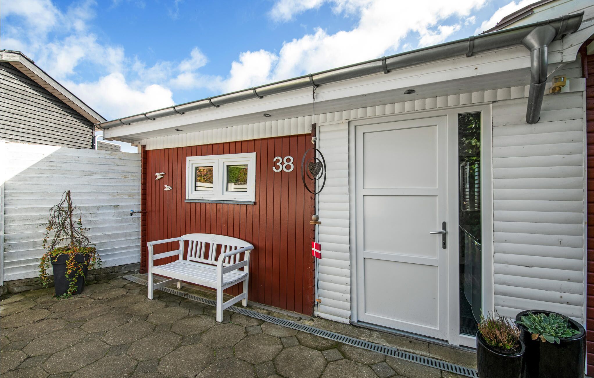 A building with a white exterior, a red door, and a white bench outside.
