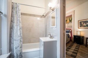 Un baño moderno con ducha, lavamanos y espejo.