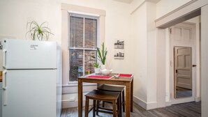 A compact kitchen with a refrigerator, wooden table, and chairs.