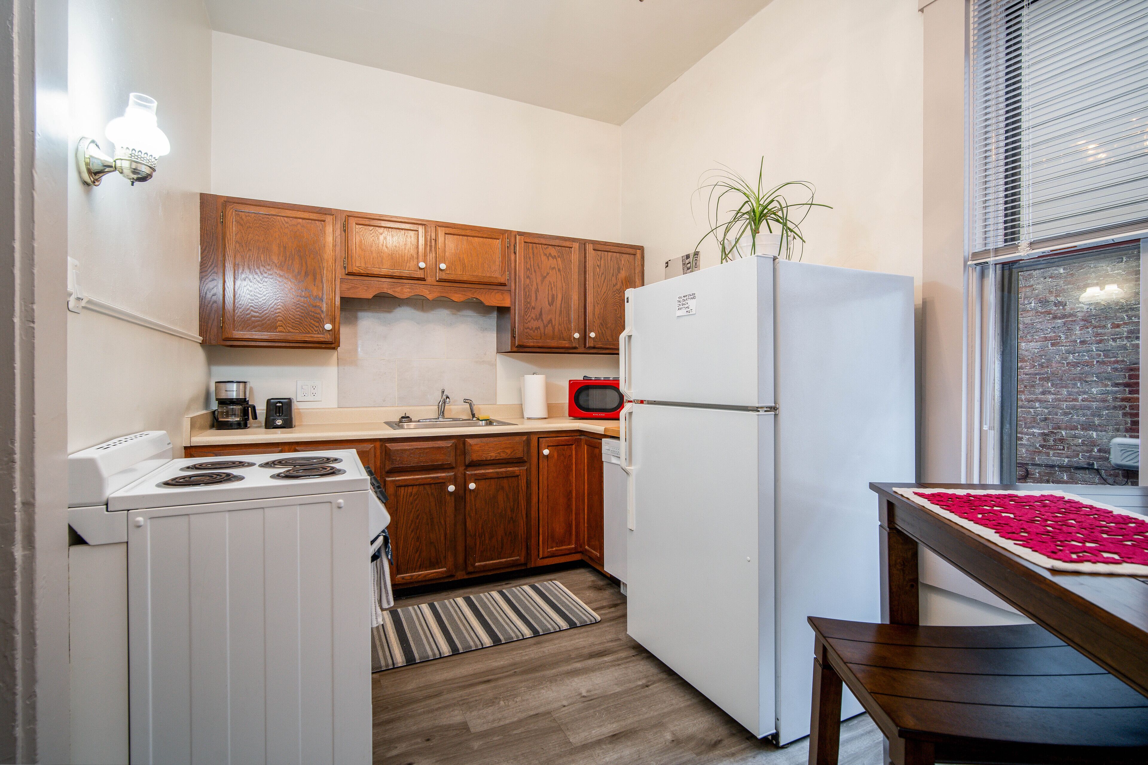 Une cuisine de taille réduite, avec des meubles en bois, un réfrigérateur blanc, une cuisinière et un four à micro-ondes.