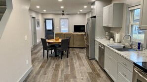 Una cocina moderna con comedor, electrodomésticos de acero inoxidable y suelo de madera.