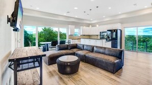 A spacious living area with a large sectional sofa, a wooden coffee table, and a TV mounted on the wall. - 40-Acre Private Ranch  Pool  2 Homes Near Austin.  (Cedar Creek)