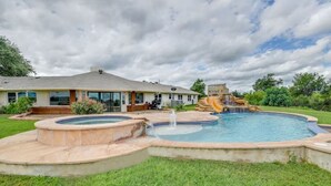 A backyard with a swimming pool, a waterfall feature, and a house with a large deck. - 40-Acre Private Ranch  Pool  2 Homes Near Austin.  (Cedar Creek)