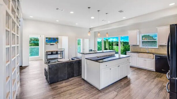 A modern kitchen with white cabinetry, a central island, and pendant lighting. - 40-Acre Private Ranch  Pool  2 Homes Near Austin.  (Cedar Creek)