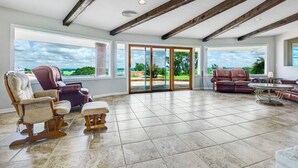 A spacious living room with a large sliding glass door leading to a patio, a fireplace, and a view of the outdoors. - 40-Acre Private Ranch  Pool  2 Homes Near Austin.  (Cedar Creek)