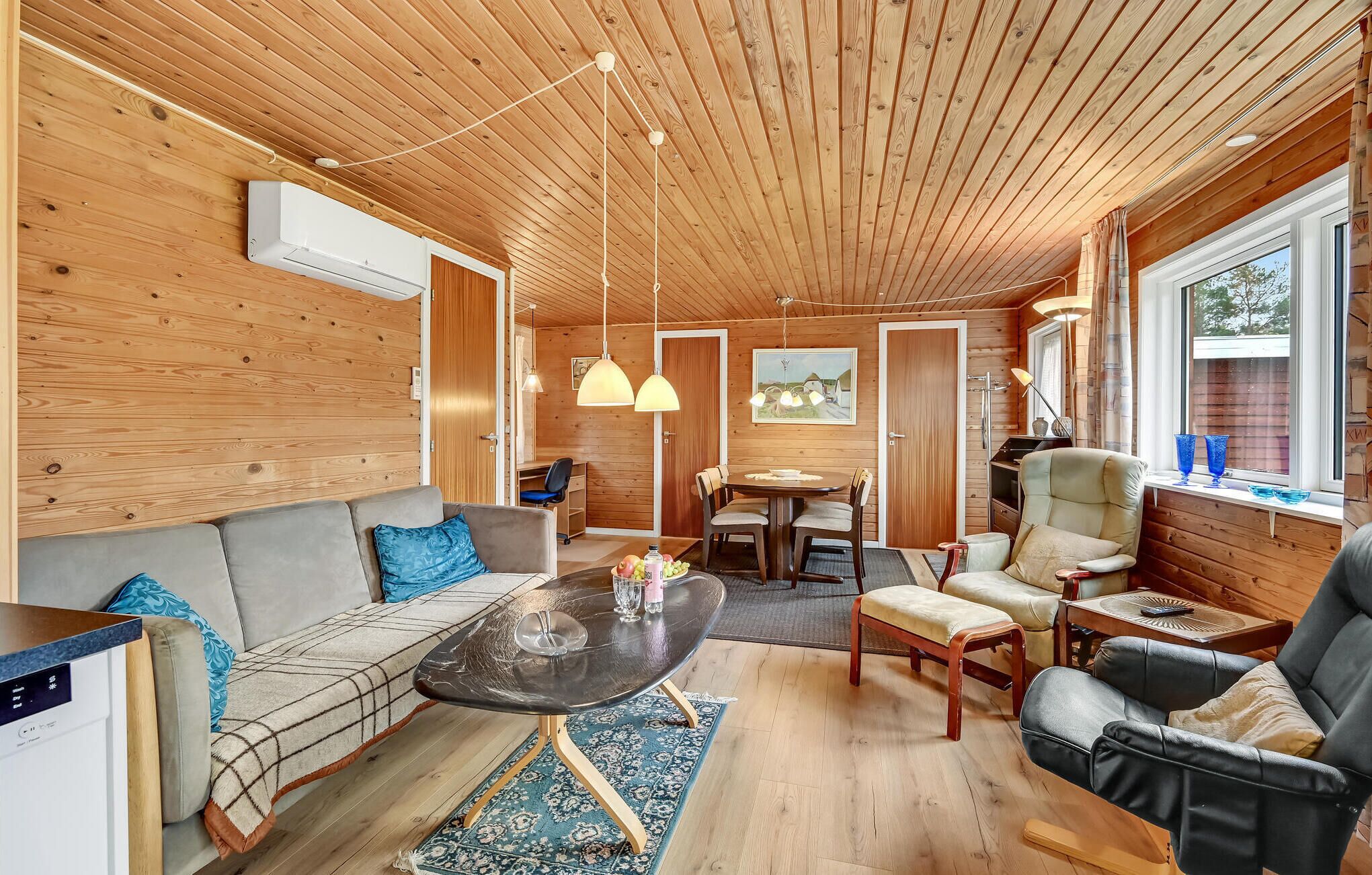 L’intérieur chaleureux d’un chalet avec un plafond en bois, un canapé, une table à manger et une chaise.