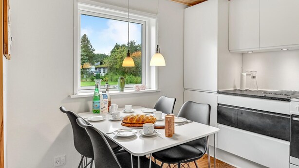 Cocina moderna con alacenas blancas, una mesa de comedor para dos personas y vistas a zonas verdes.