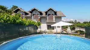Une piscine à l’eau d’un bleu cristallin, entourée d’une zone délimitée par une clôture et agrémentée d’une végétation luxuriante.
