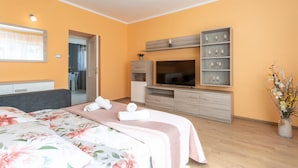 Une chambre d’hôtel avec un lit, une télévision, une petite armoire et un vase avec des fleurs.