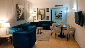 Un saló modern amb un sofà blau, una taula de dinar rodona amb cadirees i obres d'art a les parets.