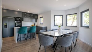 Une cuisine moderne avec des meubles de couleur grise, un îlot central doté de tabourets de bar et une table à manger avec des chaises grises.
