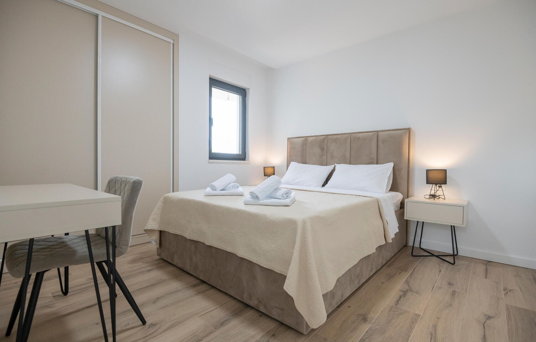 Une chambre d’hôtel comprenant un lit, un bureau, une chaise et deux tables de chevet avec des lampes.