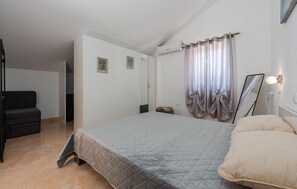 Une chambre à coucher comprenant un lit, une chaise, une armoire et un appareil de climatisation.