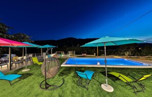 Un área junto a la piscina con tumbonas y sombrillas.