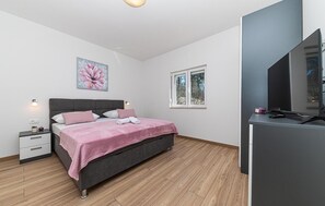 Un dormitorio con cama, mesita de noche y ventana con vistas a árboles.