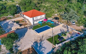 Una villa moderna con piscina, mobiliario de exterior y jardín.