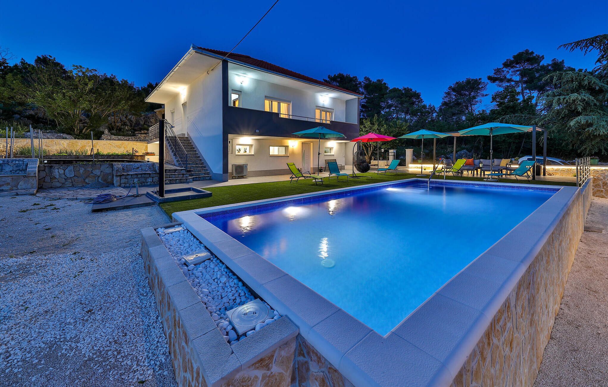 A two-story house with a swimming pool, outdoor seating, and a staircase leading to the upper floor.