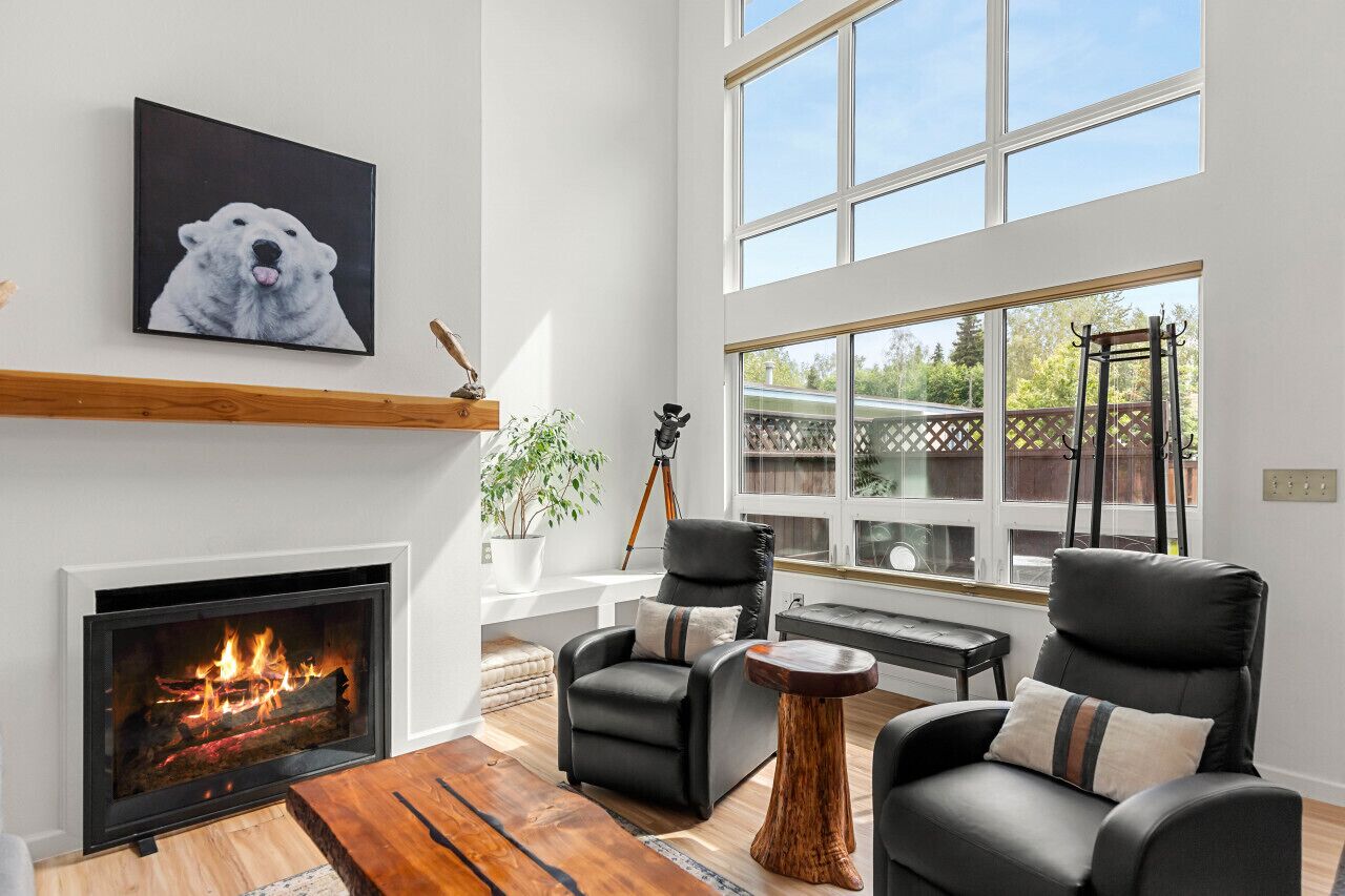 A modern living room with a fireplace, leather sofas, a coffee table, and a large window with a view.