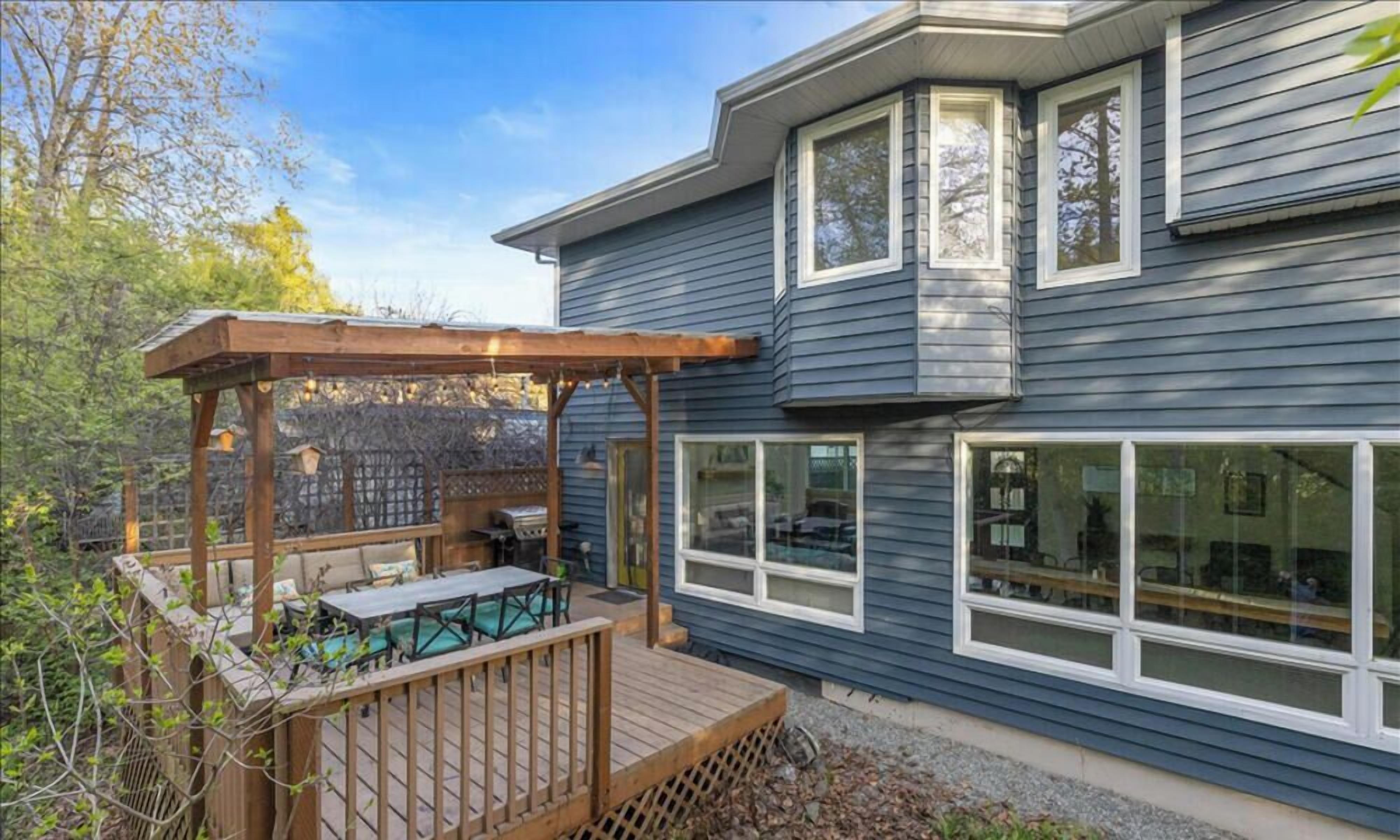 A residential property with a covered patio, a deck, and a large windowed room.