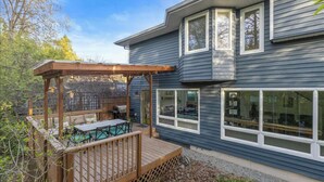 Una casa moderna con terraza, pérgola y zona de barbacoa.