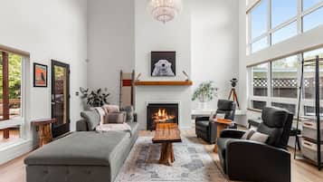 A modern living room with a fireplace, a large window, and a chandelier.